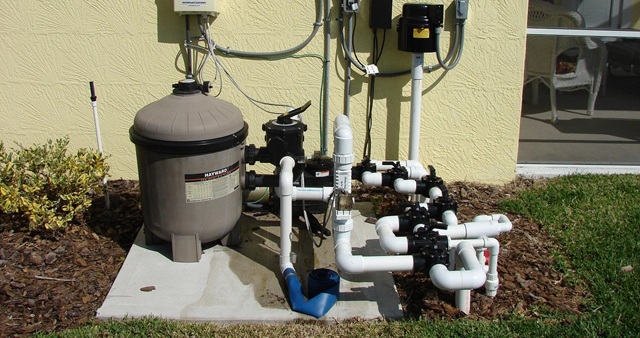 A complex swimming pool equipment pad showing a pump, filter, heater, and multiple PVC pipes with 3-way valves